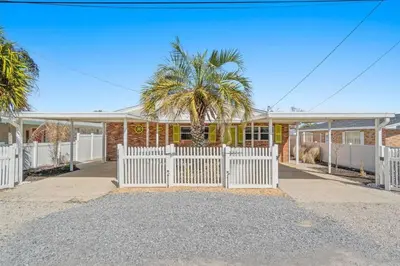 a white fence in front of a house with a palm tree at Paradise Found in Panama City Beach