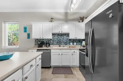 a kitchen with white cabinets and a stainless steel refrigerator at 30A-SEA For Yourself - Seagrove Highlands in Santa Rosa Beach