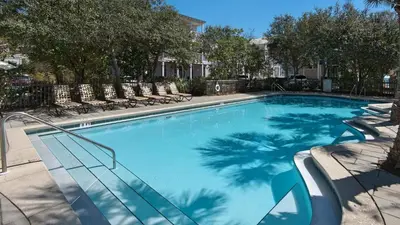 a large blue swimming pool with chairs and trees at Bless My Sol in Santa Rosa Beach