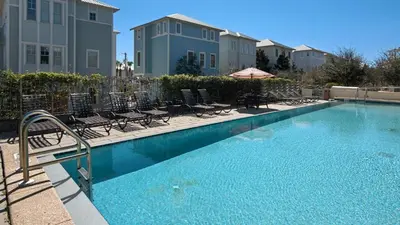 a swimming pool with chairs and an umbrella at Bless My Sol in Santa Rosa Beach