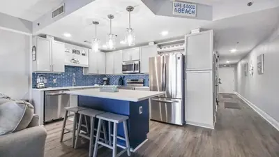 a kitchen with white cabinets and a refrigerator at Deep Blue at Laketown Wharf #214 by Nautical Properties in Panama City Beach
