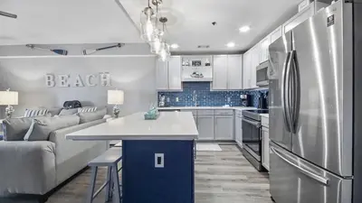 a kitchen and living room with a couch and a refrigerator at Deep Blue at Laketown Wharf #214 by Nautical Properties in Panama City Beach