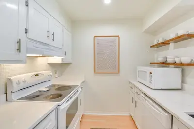 a white kitchen with white cabinets and a microwave at Santa Rosa Beach Townhome Patio, Walk to Beach! in Santa Rosa Beach