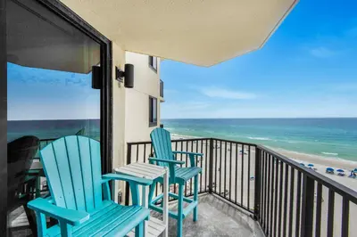 two chairs sitting on a balcony looking out at the ocean at Sunbird 709W Beach Life in Panama City Beach