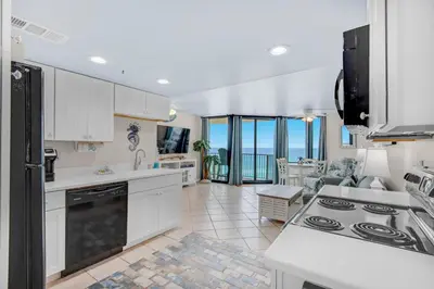 a kitchen with white cabinets and a view of the ocean at Sunbird 709W Beach Life in Panama City Beach