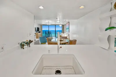 a white kitchen with a sink and a table at One Seagrove Place #1308 - 