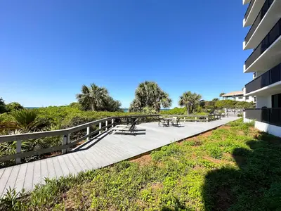 a walkway next to a building with tables and benches at One Seagrove Place #1308 - 