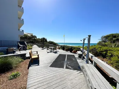 a wooden deck with benches and the ocean in the background at One Seagrove Place #1308 - 