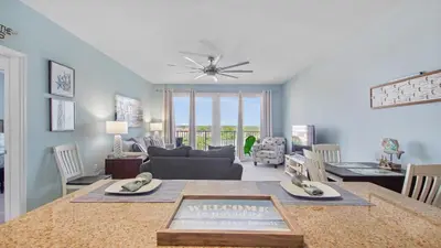 a living room with a table with a welcome sign on it at Shell Yeah at Laketown Wharf #730 by Nautical Properties in Panama City Beach