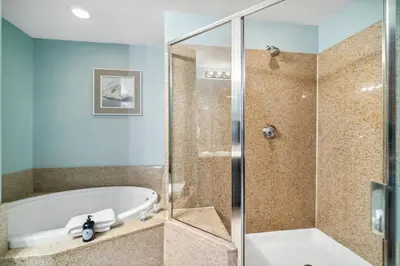 a bathroom with a tub and a glass shower stall at Keep It Beachy at Laketown Wharf #611 by Nautical Properties Vacation Rentals in Panama City Beach