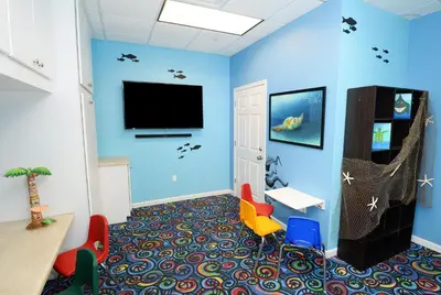 a room with a blue wall with a tv and chairs at Tidewater 2204 in Panama City Beach