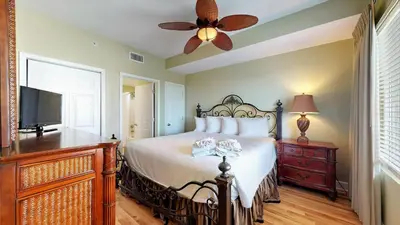 a bedroom with a bed with a ceiling fan and a television at Tidewater 2204 in Panama City Beach