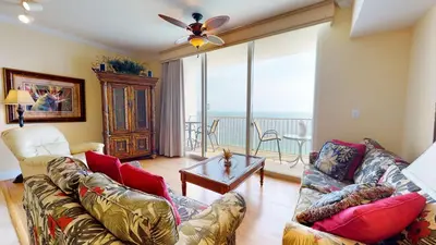 a living room with two couches and a balcony at Tidewater 2613 in Panama City Beach