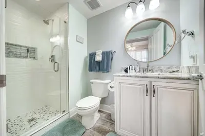 a bathroom with a toilet and a shower and a mirror at Celadon 209 in Panama City Beach