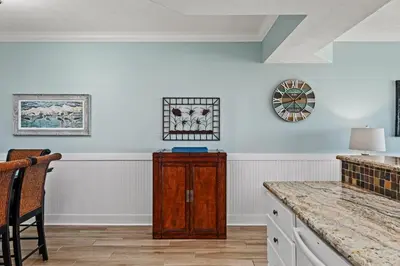 a kitchen with a wooden cabinet and a clock on the wall at Treasure Island #1505 in Panama City Beach