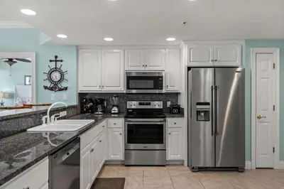 a kitchen with white cabinets and a stainless steel refrigerator at Treasure Island #0105 in Panama City Beach