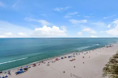 a beach with people and umbrellas and the ocean at Seychelles #1007 in Panama City Beach