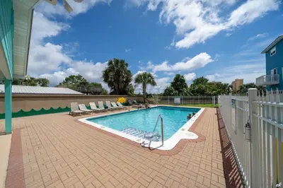 a swimming pool with chairs and a fence at Summer Towne Cottages #16 in Panama City Beach