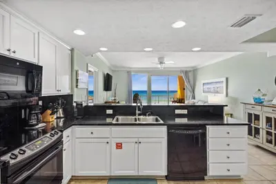 a kitchen with white cabinets and a view of the ocean at Treasure Island #0206 in Panama City Beach