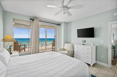 a bedroom with a bed and a balcony with the ocean at Treasure Island #0206 in Panama City Beach