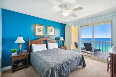 a bedroom with a bed and a balcony with the ocean at Treasure Island #1608 in Panama City Beach