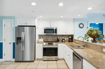 a kitchen with white cabinets and a stainless steel refrigerator at Treasure Island #1608 in Panama City Beach