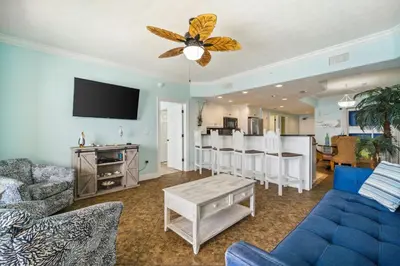 a living room with a blue couch and a table at Treasure Island #1005 in Panama City Beach