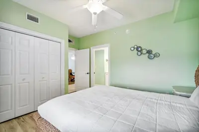 a bedroom with a white bed and a ceiling fan at Treasure Island #1005 in Panama City Beach