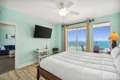 a bedroom with a bed and a flat screen tv at Treasure Island #1005 in Panama City Beach