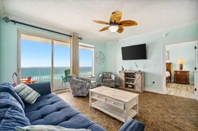 a living room with a blue couch and a view of the ocean at Treasure Island #1005 in Panama City Beach