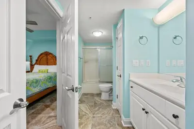 a bathroom with a sink and a toilet and a bed at Treasure Island #1506 in Panama City Beach