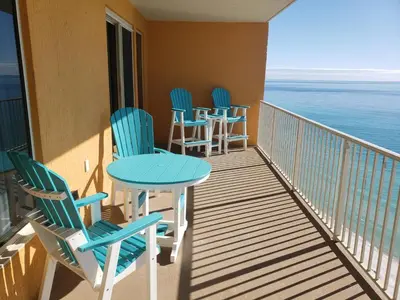 a balcony with chairs and tables and the ocean at Treasure Island #1506 in Panama City Beach