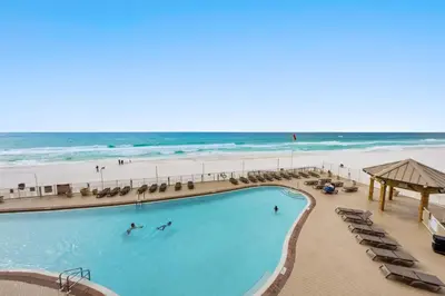 a swimming pool next to a beach with the ocean at Treasure Island #0310 in Panama City Beach