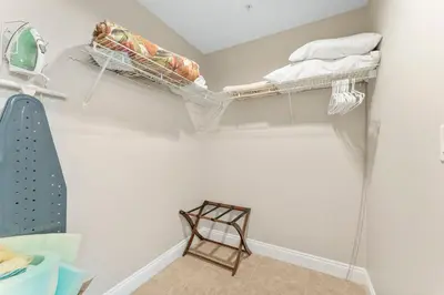 a walk in closet with two shelves and a chair at Treasure Island #0507 in Panama City Beach