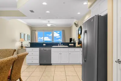 a kitchen with white cabinets and a black refrigerator at Treasure Island #0507 in Panama City Beach
