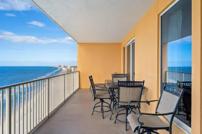 a balcony with chairs and a table and the ocean at Treasure Island #1807 in Panama City Beach