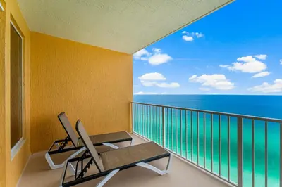 a balcony with two chairs and a view of the ocean at Treasure Island #2306 in Panama City Beach
