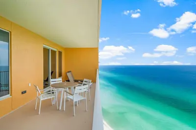 a balcony with a table and chairs and the ocean at Treasure Island #2306 in Panama City Beach