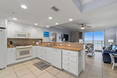 a kitchen with white cabinets and a view of the ocean at Treasure Island #0110 in Panama City Beach