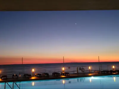 a swimming pool with a view of the ocean at sunset at Treasure Island #0110 in Panama City Beach