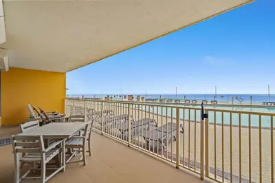 a balcony with tables and chairs and a view of the beach at Treasure Island #0110 in Panama City Beach