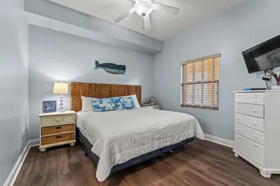 a bedroom with a bed and a dresser and a tv at Treasure Island #0409 in Panama City Beach