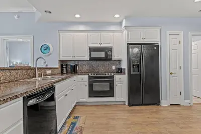 a kitchen with white cabinets and a stainless steel refrigerator at Treasure Island #0409 in Panama City Beach