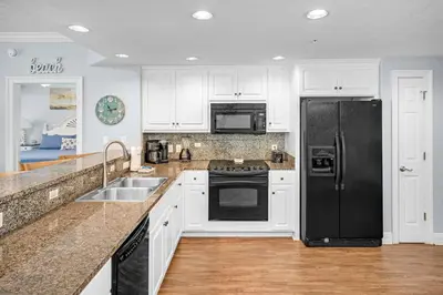 a kitchen with white cabinets and a black refrigerator at Treasure Island #2109 in Panama City Beach