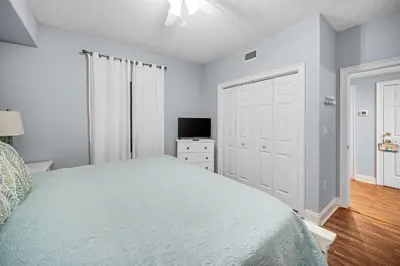 a white bedroom with a bed and a television at Treasure Island #2109 in Panama City Beach
