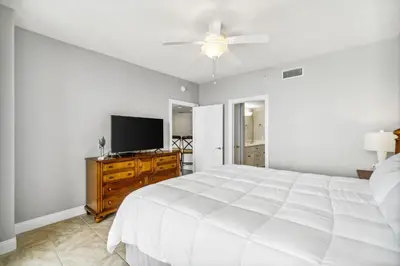 a bedroom with a white bed and a flat screen tv at Treasure Island #1808 in Panama City Beach