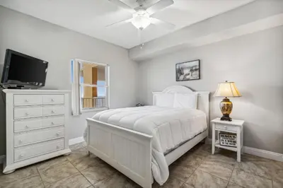 a bedroom with a white bed and a tv at Treasure Island #1808 in Panama City Beach