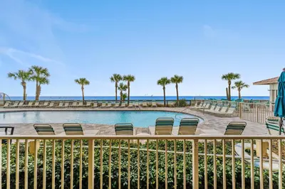 a swimming pool with chairs and the ocean in the background at Gulf Crest #0106 in Panama City Beach