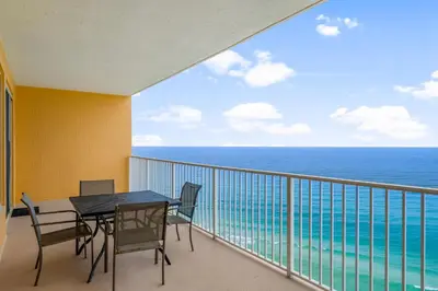 a balcony with a table and chairs and the ocean at Treasure Island #1609 in Panama City Beach