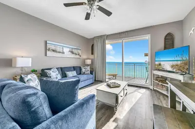 a living room with a blue couch and a tv at Sterling Reef 1704 in Panama City Beach